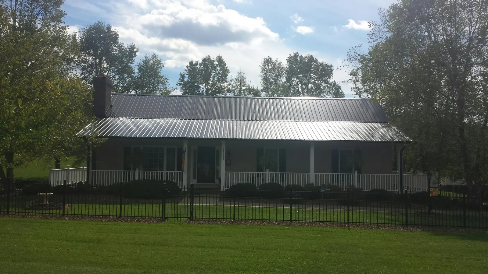 Gray metal roof on a brick ranch with a full width front porch — Gutter Guard Installation work by our crew in Volin