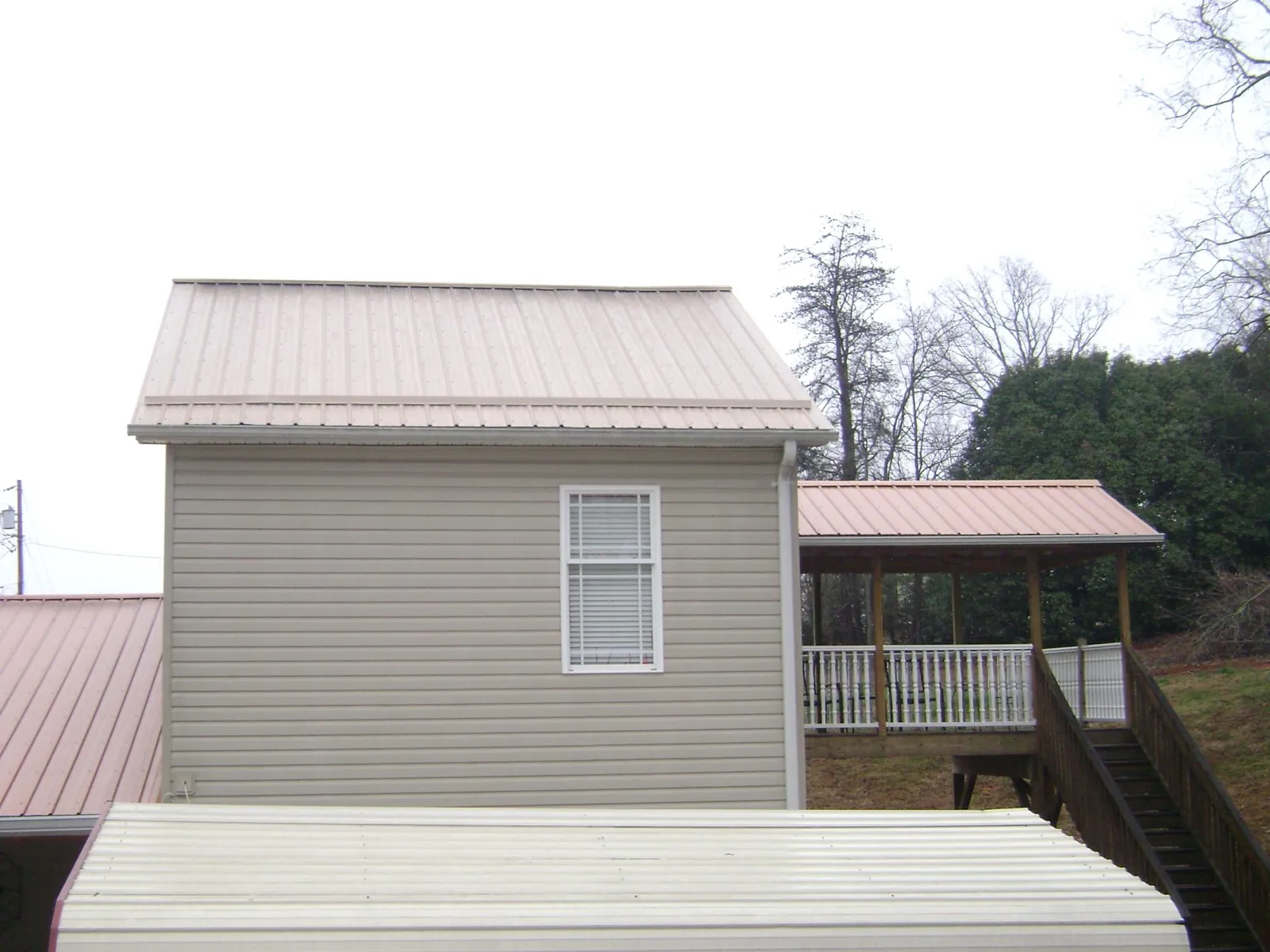 Tan metal roofs on a two story addition and attached porch, from a Roof Replacement job in Volin